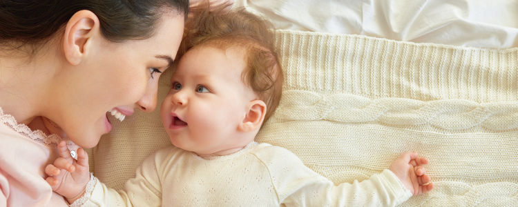 happy family. mother playing with her baby in the bedroom.